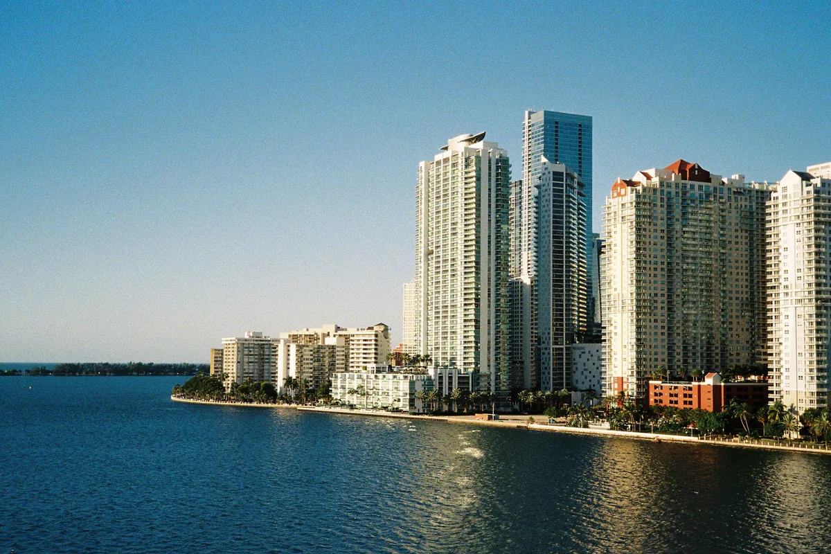 Oceanfront high-rise condominium towers with glass balconies along a sunny Florida coastline